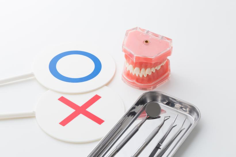 顎模型と歯科治療器具と○×と書かれた札