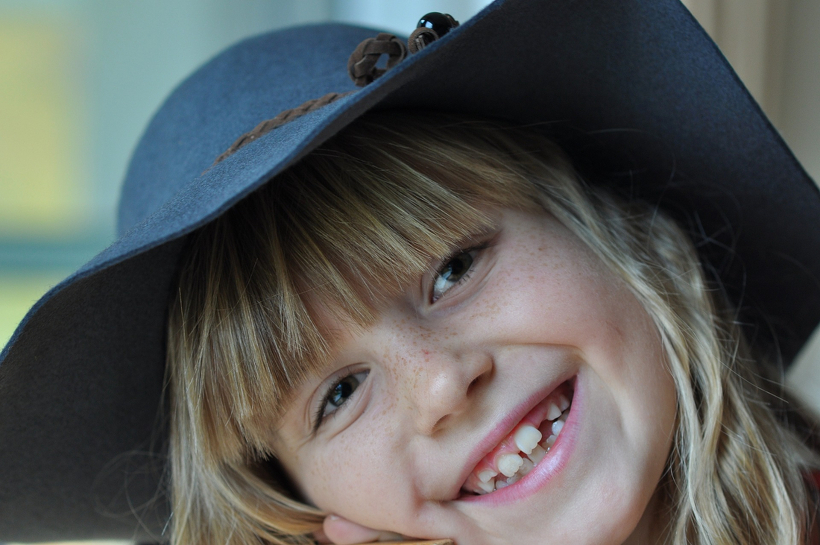 笑顔でこちらを見る青い帽子の女の子
