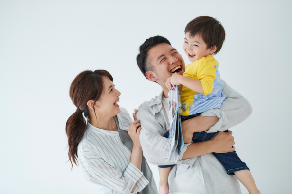 笑顔の男の子を抱き上げて笑う父親と、それに寄り添い笑う母親