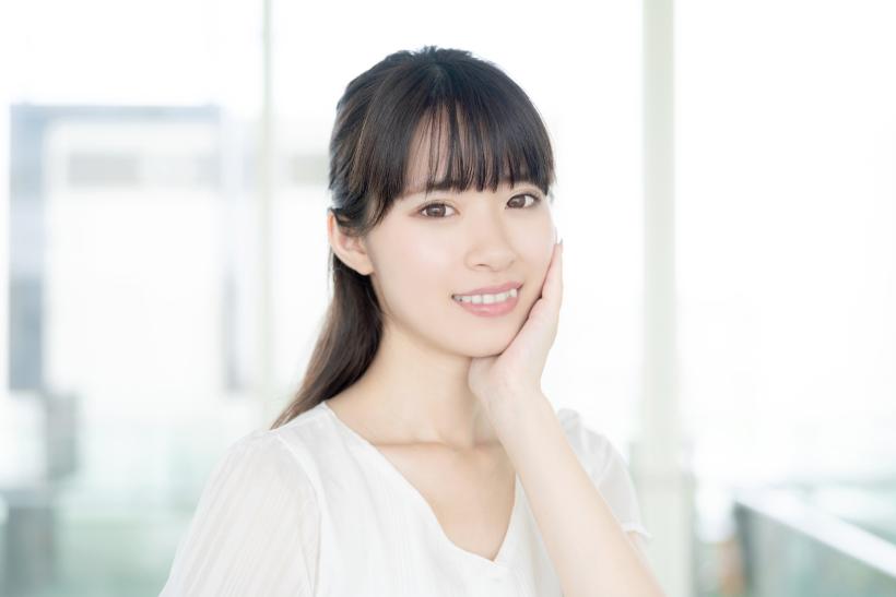 左頬を手で覆って笑っている女性