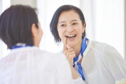 鏡で口の中を見る女性