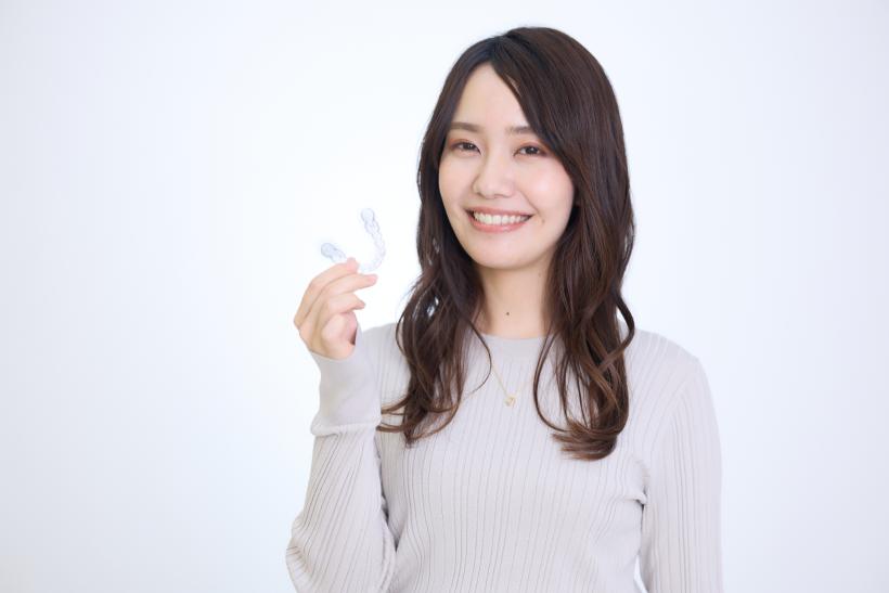 インビザラインを手に持つグレーの服の女性