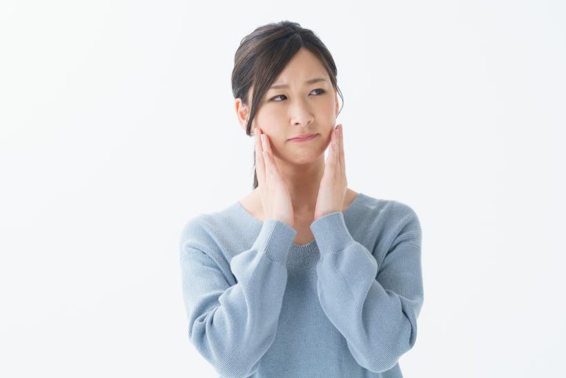 両手で頬をおさえる青い服の女性