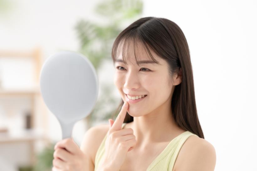 手鏡を持ち自分の前歯を指差す女性
