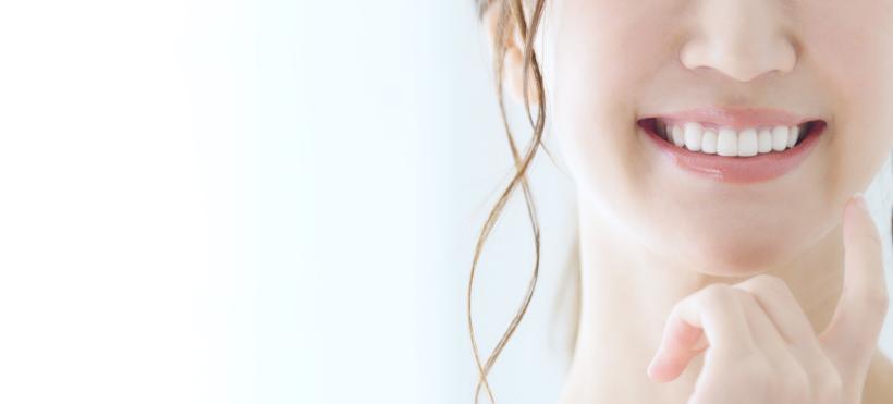 手鏡を持ち自分の歯を指差す白い服の女性