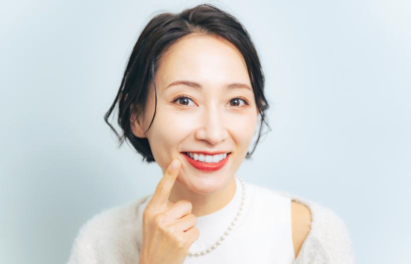 自分の歯を指差す白い服の女性