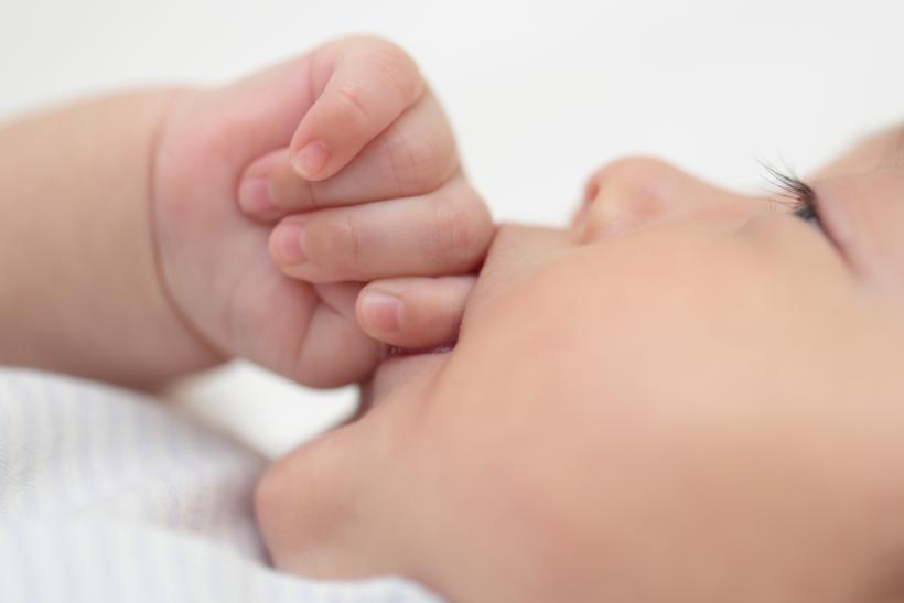 指しゃぶりをしている赤ちゃんの横顔